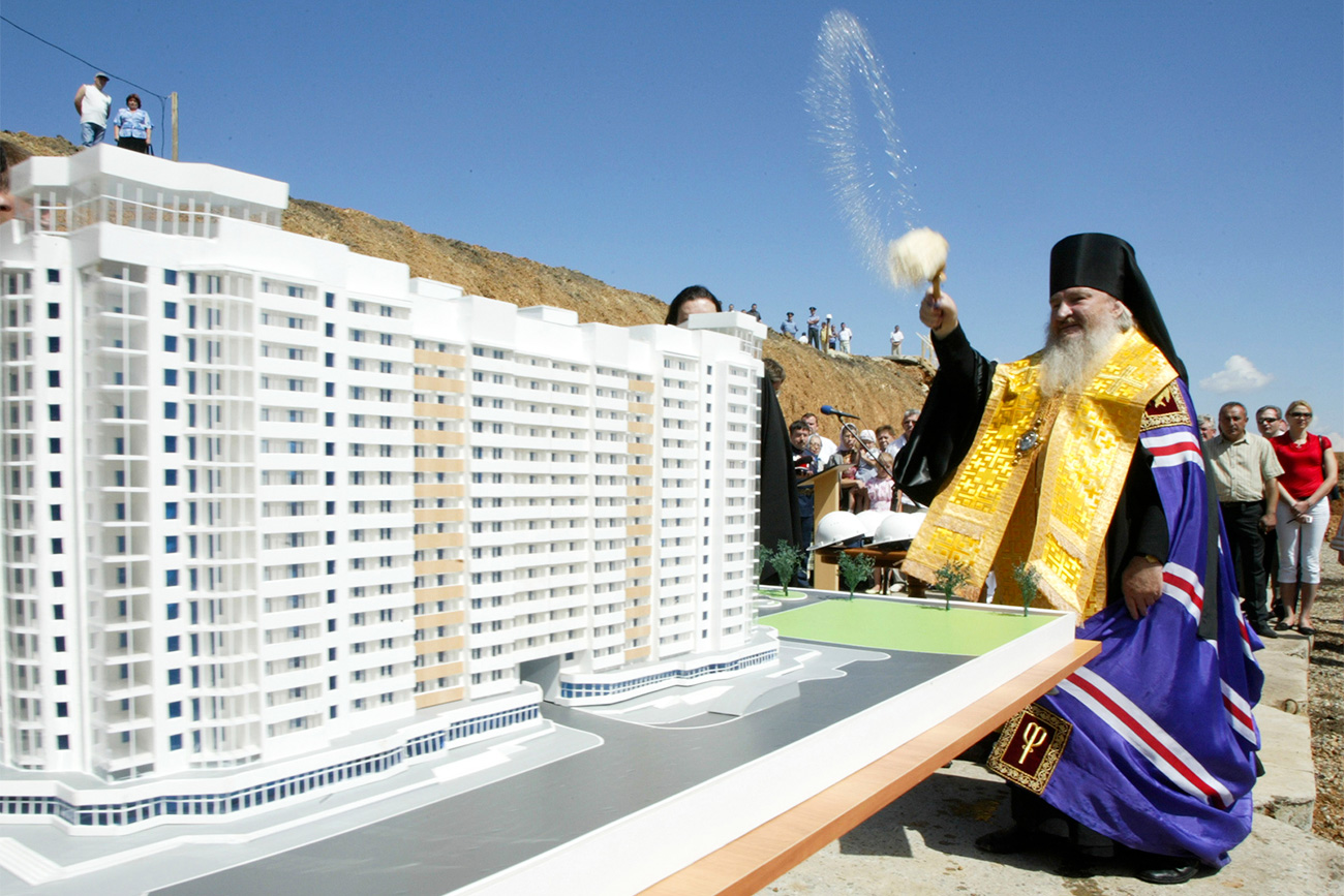 Seorang pendeta Ortodoks memberkati sebuah model blok rumah susun di kota Stavropol, Rusia selatan. Sumber: Reuters