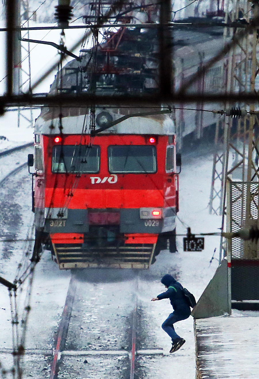 A passenger jumps from the platform at a railway station.