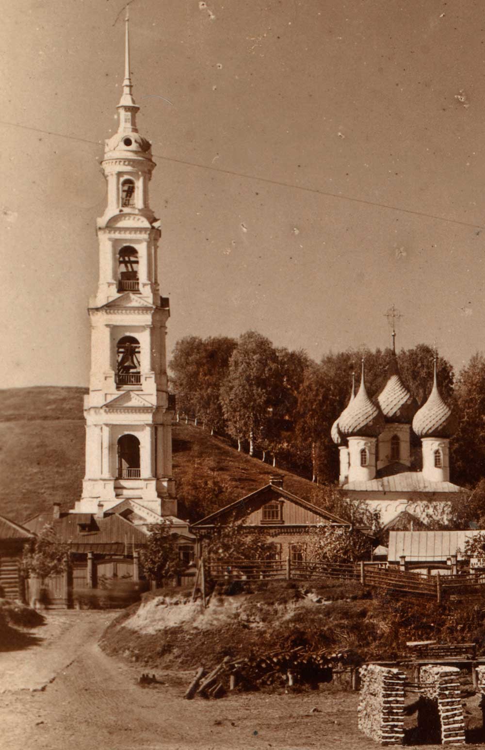 Bell tower of St. George & Cathedral of Entry of Christ into Jerusalem. East view from Volga River. Foreground: stacked firewood. Summer 1910.