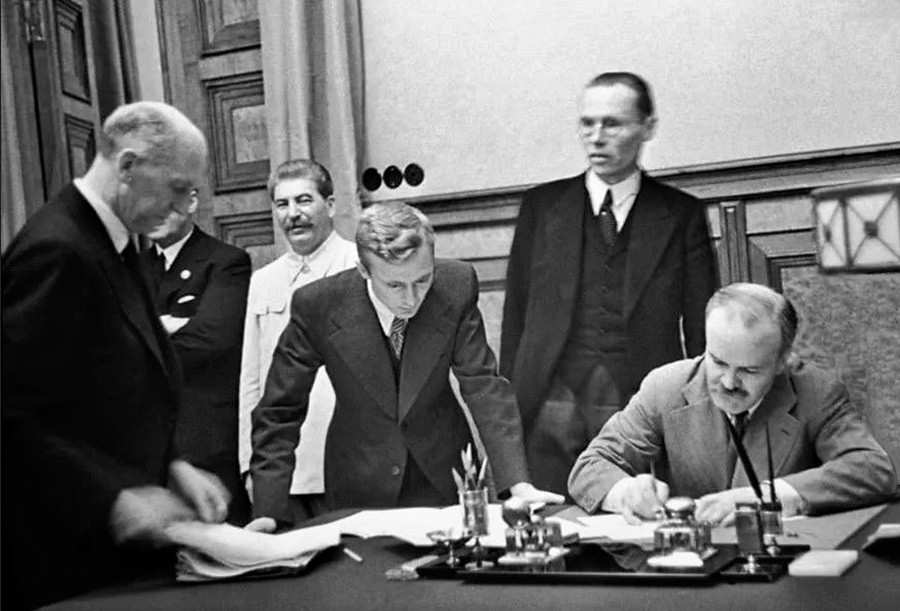 Molotov signing the German-Soviet Frontier Treaty, a supplementary protocol to the Molotov-Ribbentrop pact. Stalin can be noticed behind his back.