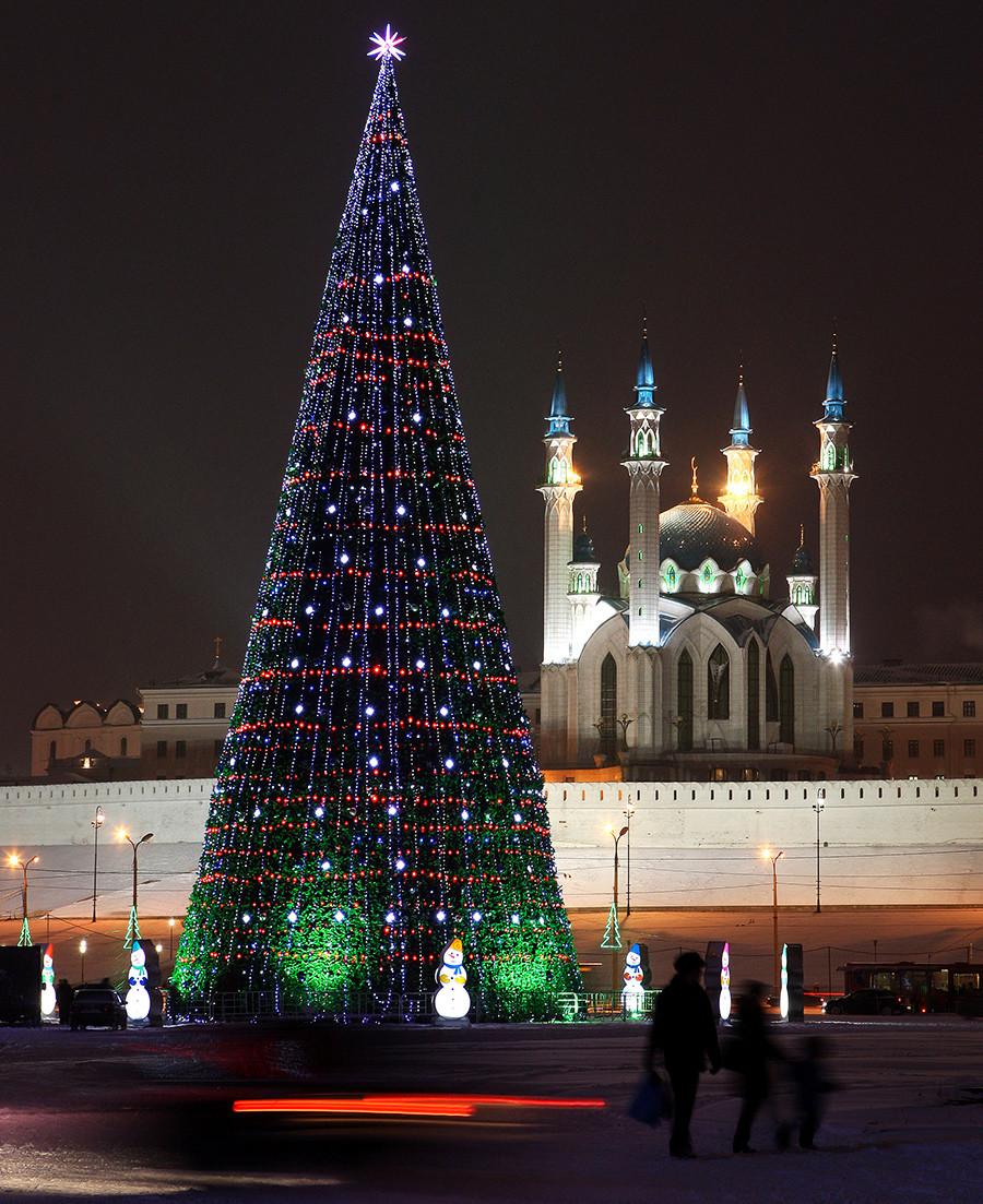 Хора минават покрай новогодишна елха в град Казан. Джамията 