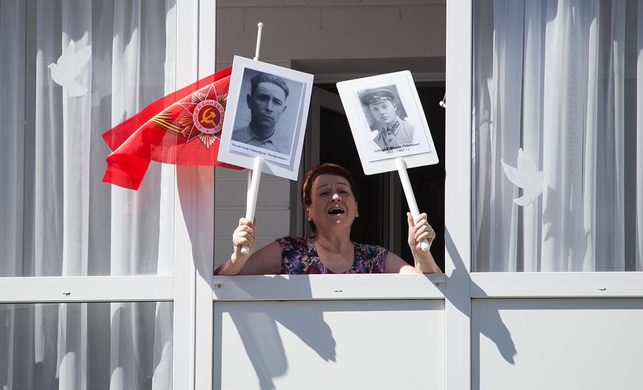 A Tyumen resident with portraits of the veterans of the Great Patriotic War sings wartime songs together with participants of the 'Home Parade' initiative. 