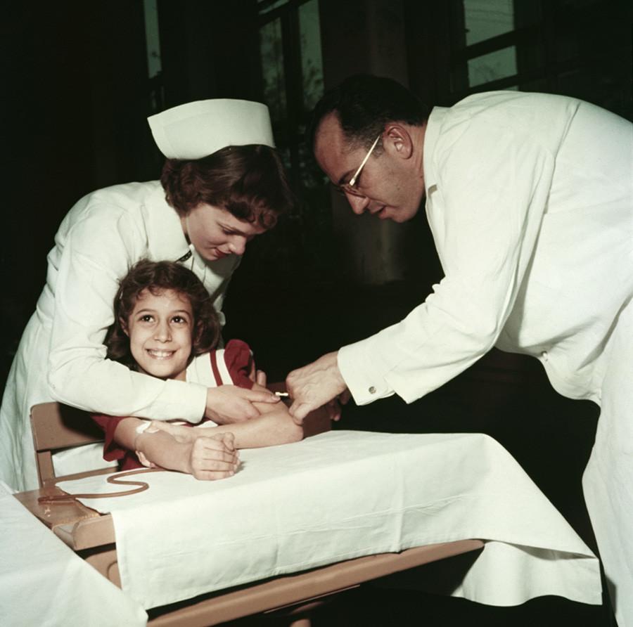 Dr. Jonas E. Salk and a nurse administer a polio vaccine to Pauline Antloger at Sunnyside school in Pittsburgh, Pennsylvania. 
