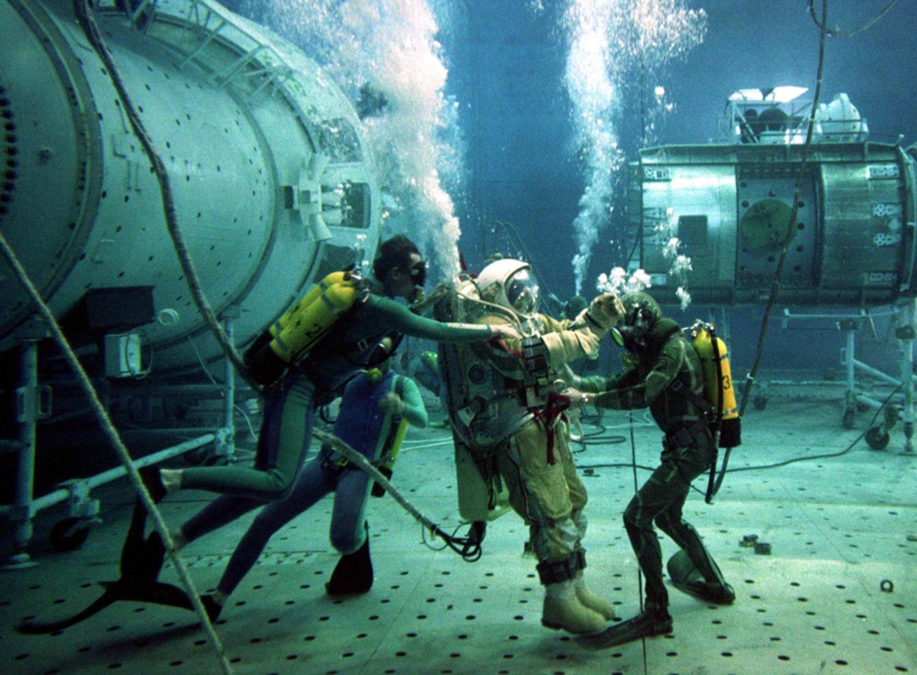 Russian test instructor Oleg Pushkar is assisted by divers during underwater tests on a replica of the damaged Mir space station July 4. 1997. 