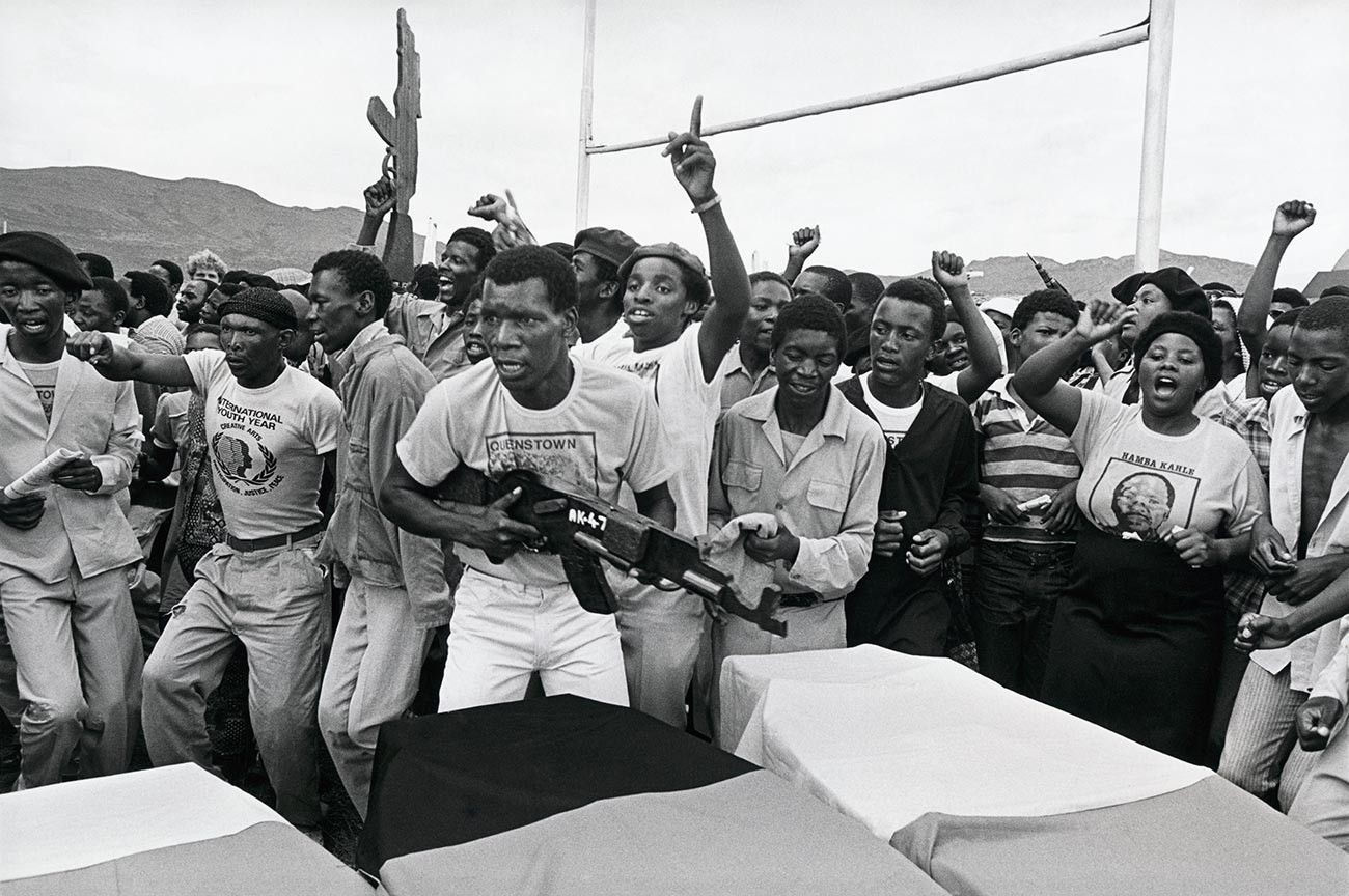 Enlutados acenam com réplicas de armas de madeira e cantam em apoio ao banido Congresso Nacional Africano no funeral dos militantes do CNA mortos em Queenstown, na África do Sul