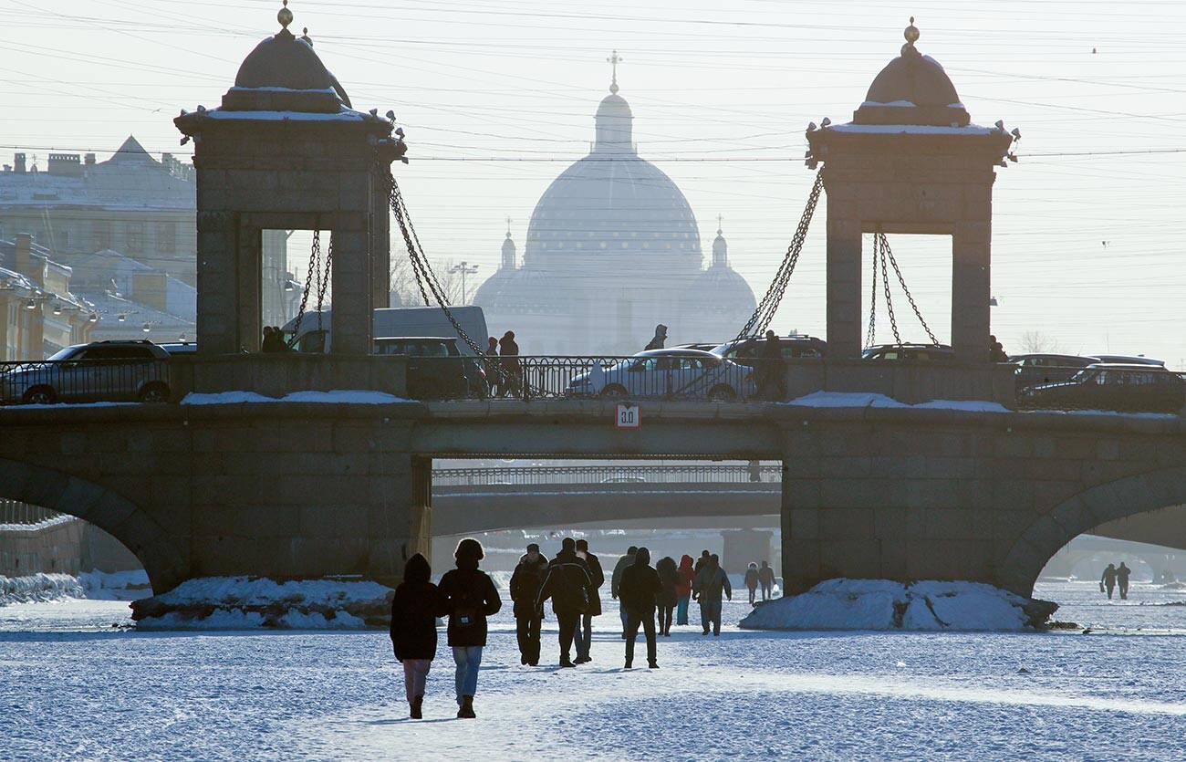 People walk on ice on the frozen Fontanka River in St.Petersburg, Russia, Wednesday, March 7, 2018, with Troitsky (Trinity) Cathedral in the background. The temperature in St. Petersburg dropped to minus 12 degrees Centigrade (10 degrees Fahrenheit 