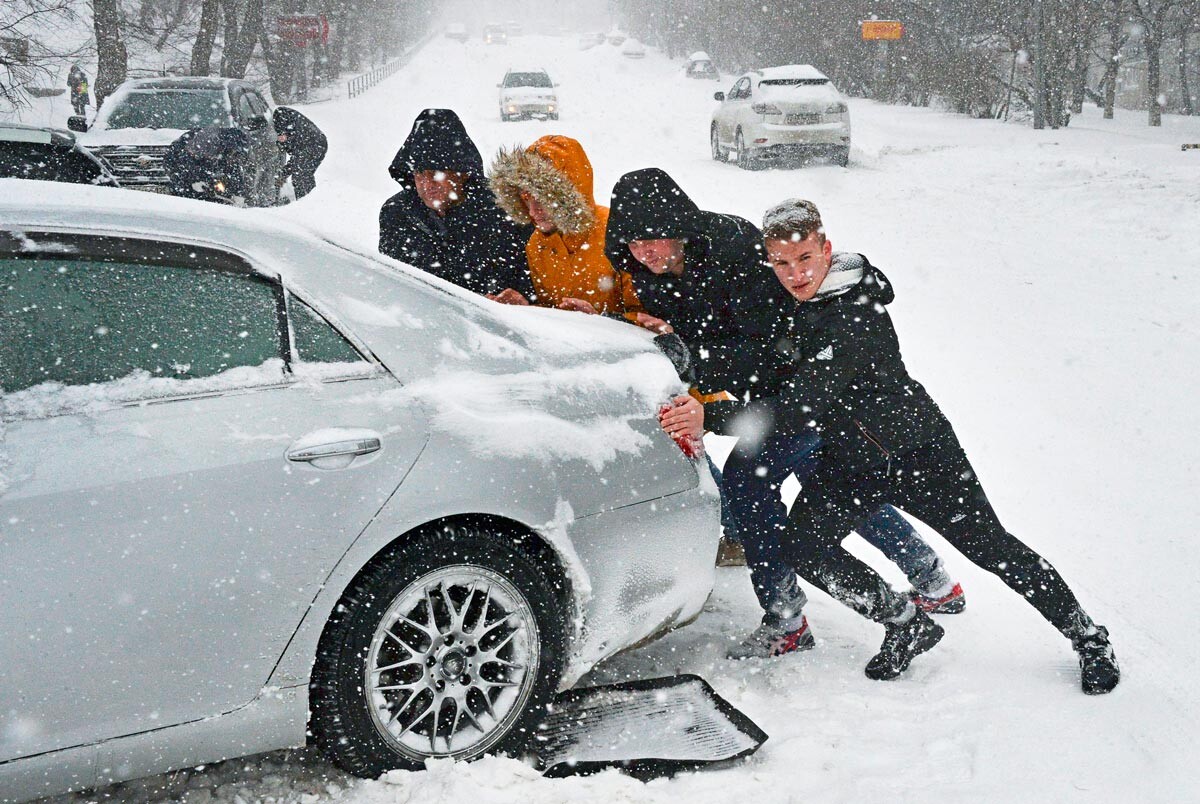 People pushing a car in Valdivostok, Russia.