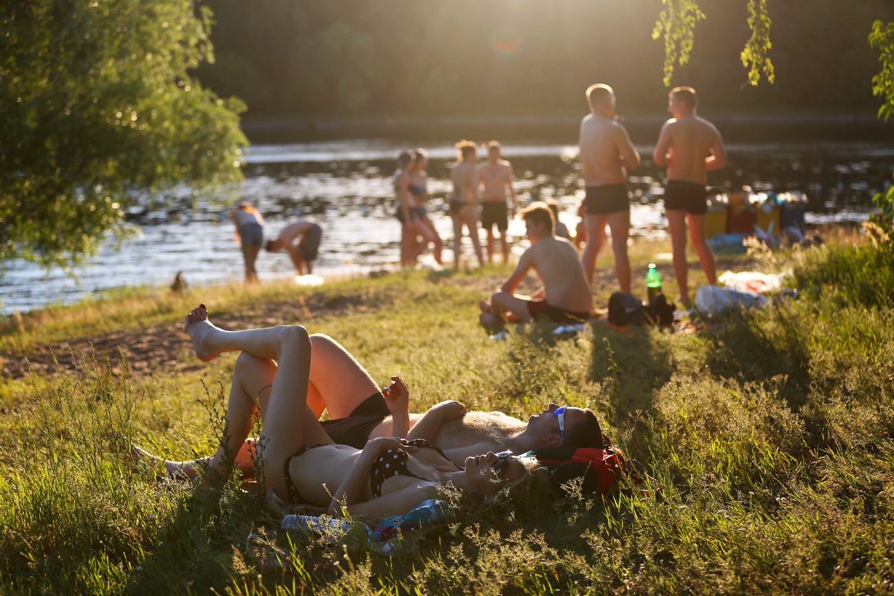 People sunbathing on a beach in Moscow’s Serebryany Bor Park. Source:  Mikhail Pochuyev/TASS 