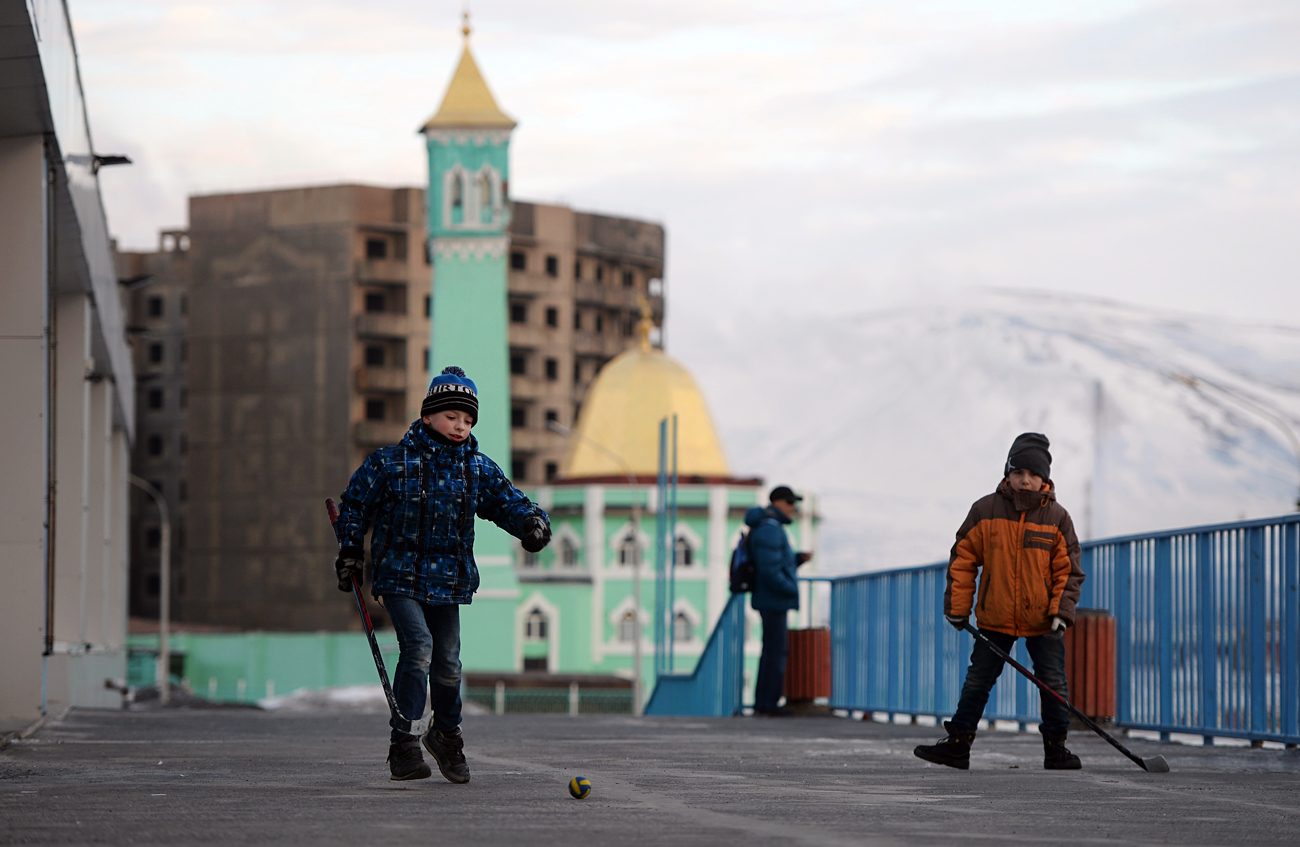 Children play hockey near the Arctic Ice Center in Norilsk. The Nurd Kamal Mosque is visible in the background. Source: Maksim Blinov/RIA Novosti