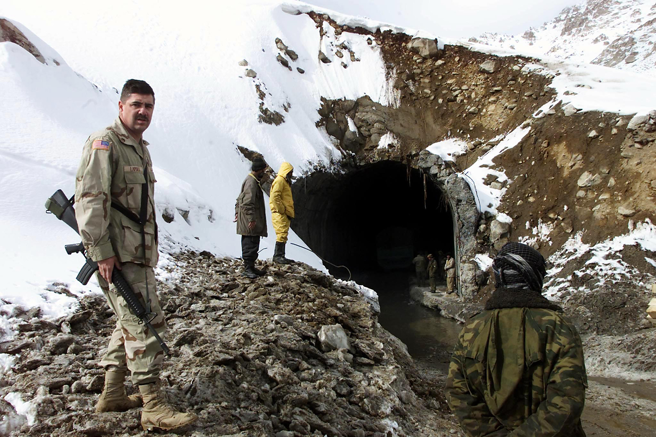 An U.S. soldier guards the Afghan workers clearing the south entrance of Salang tunnel to widen its access. Reuters