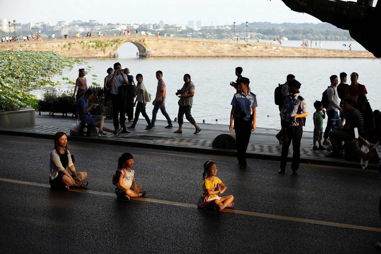 People pose for photos on an empty road near the West Lake, as police closed off many roads before G20 Summit in Hangzhou, Zhejiang Province, China / Reuters