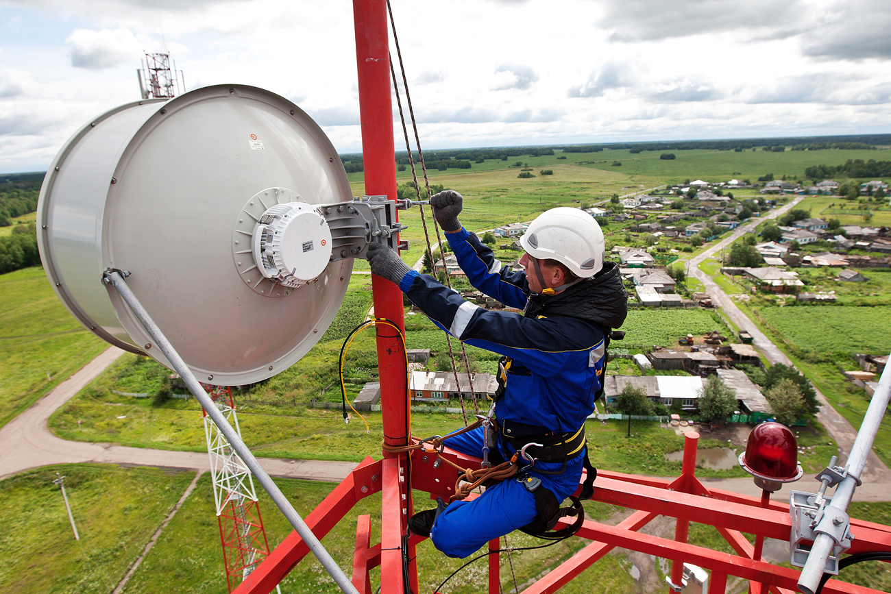 A technician attaches a radio relay antenna for cellular communications on a tower in the village of Babarykino, Russia.