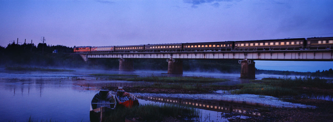 A night train speeds across a misty  river in the northern Urals region. Source: Anton Lange / Russia from the Train Window