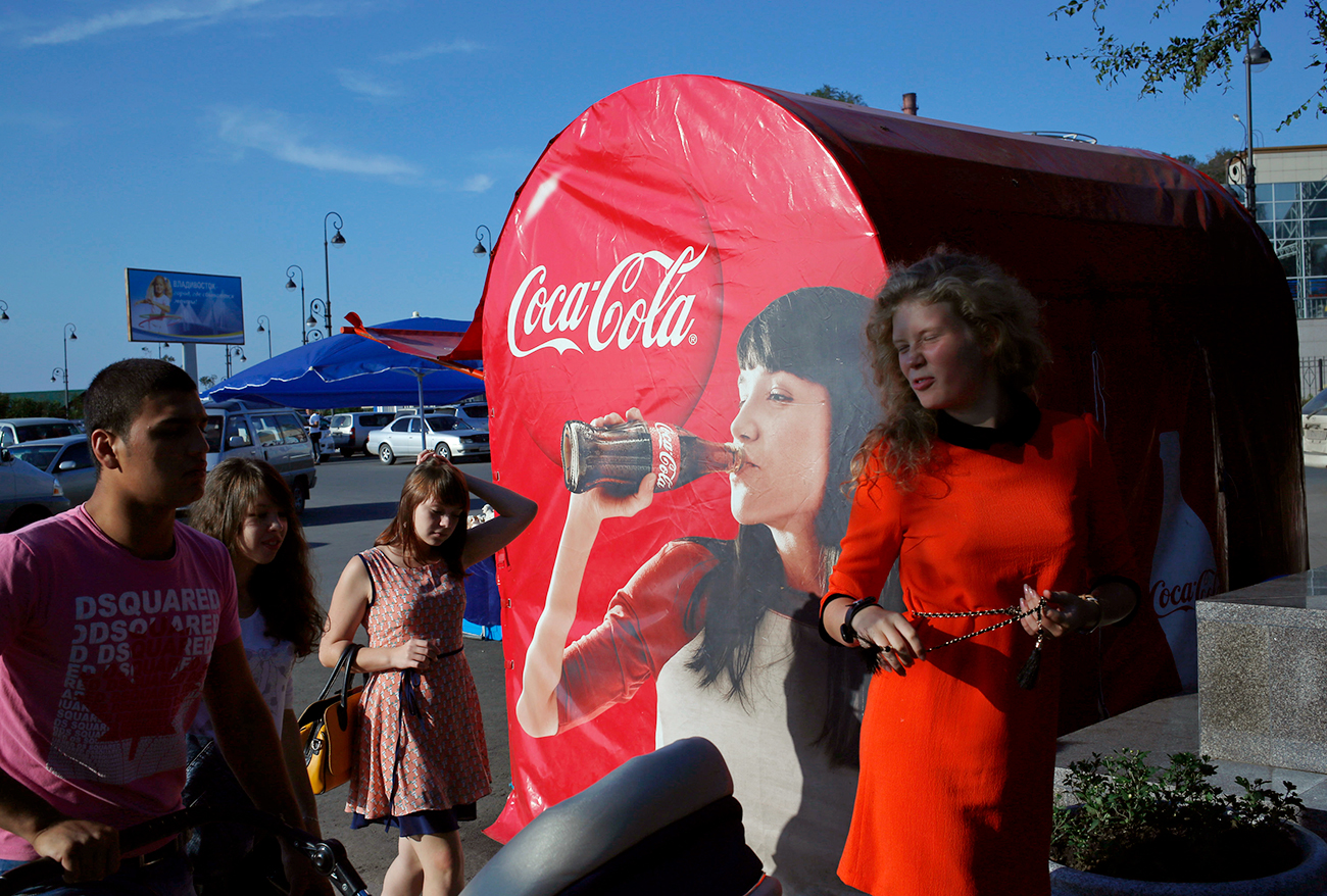 Local residents walk past a Coca-Cola booth near a beach in Vladivostok. / Photo: AP