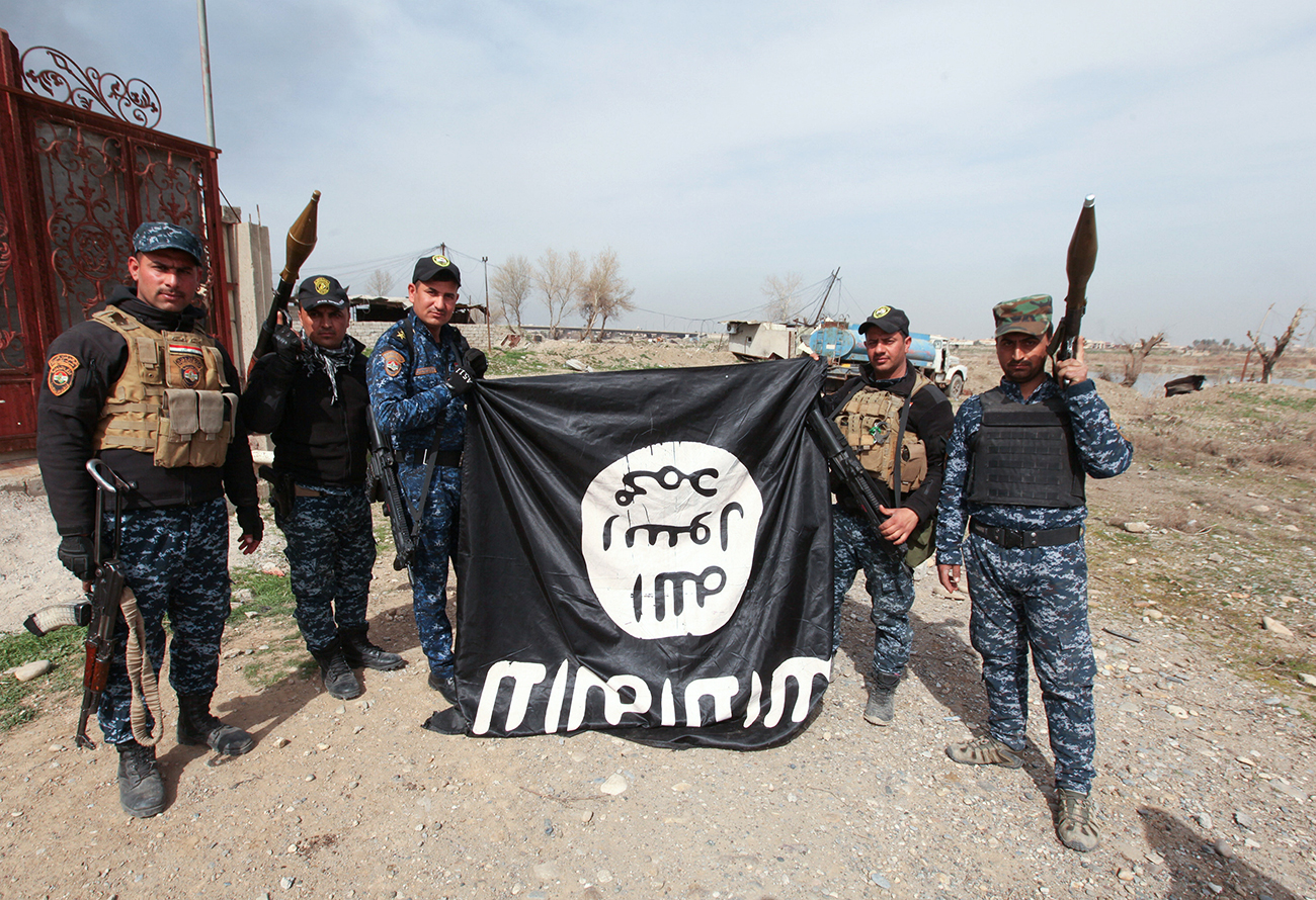 Die Mitglieder der irakischen Streitkräften mit einer ISIS-Flagge, nachdem sie die Terroristen in Mosul bekämpft haben. / Reuters