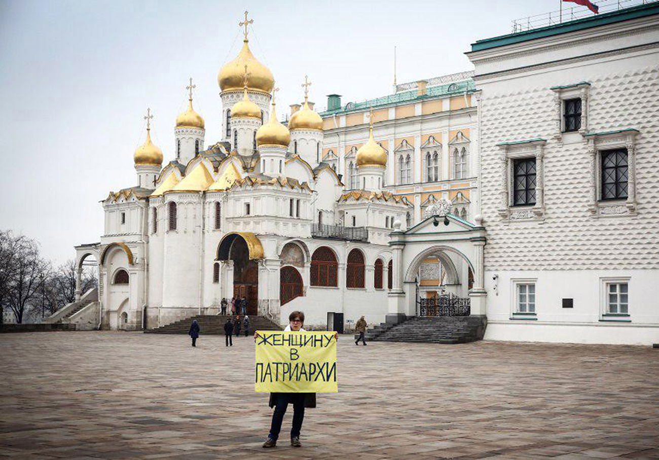A feminist activist holds a sign with a message reading "A woman for patriarch" during a protest in the Kremlin on the International Women's Day. / Photo: TASS