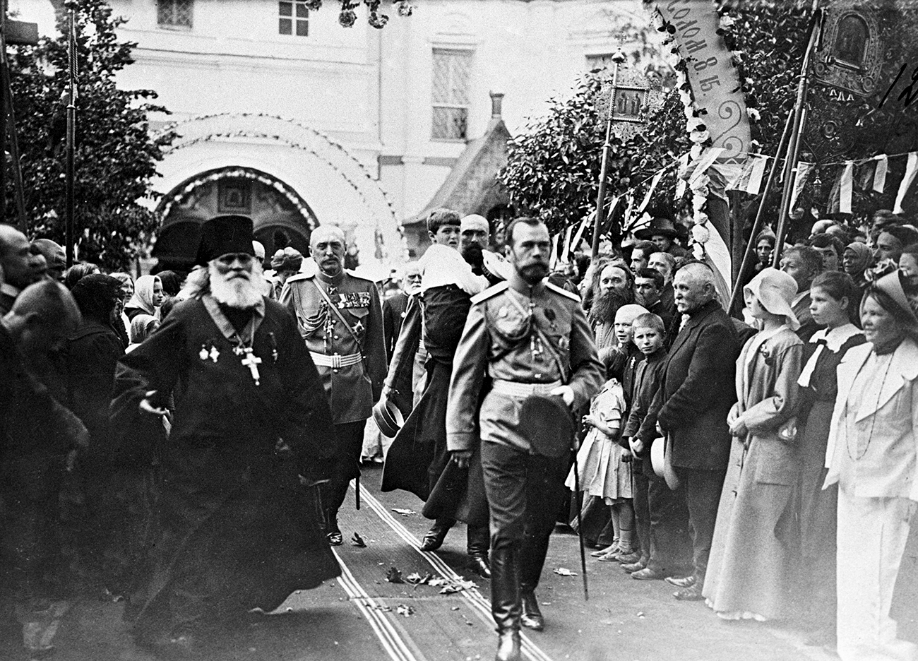 Emperor Nicholas II and Crown Prince Alexis, in the background, carried by a Cossack attendant, 1913. / RIA Novosti