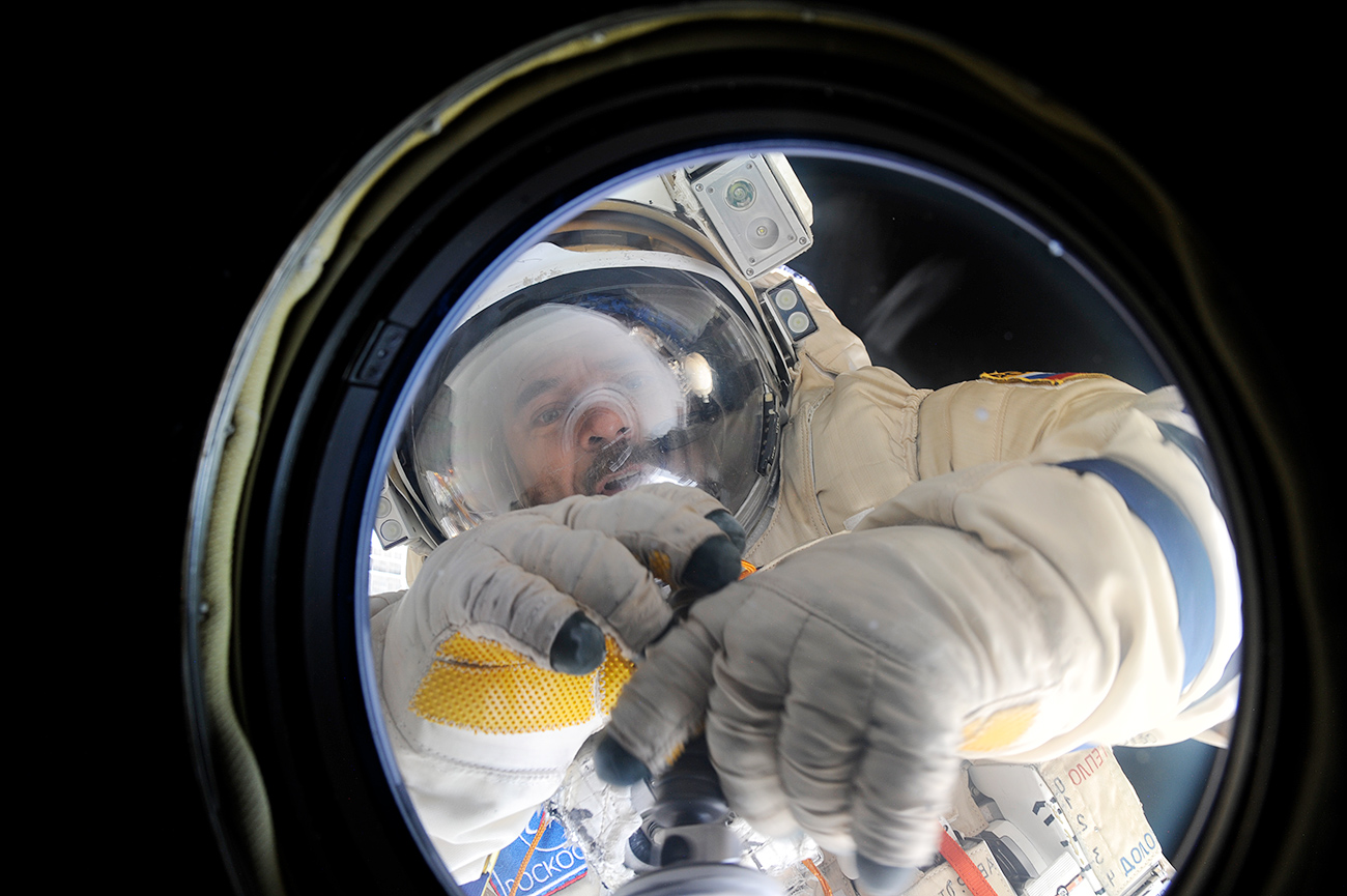 O cosmonauta Mikhail Kornienko limpa uma porta da Estação Espacial Internacional. Foto: Roscosmos