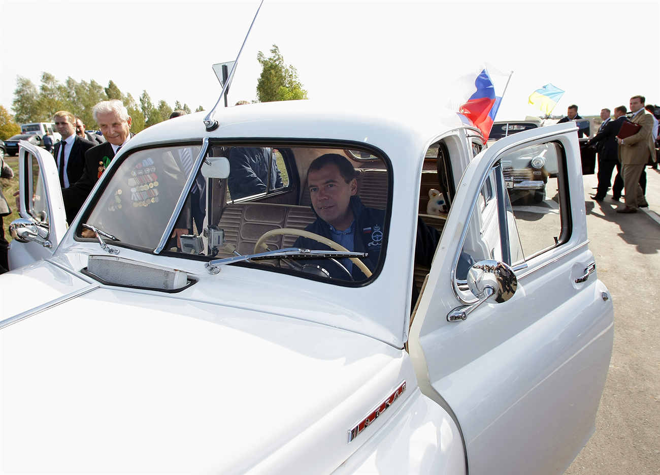 Dmitri Medvédev, durante su época como presidente, espera la llegada de un veterano de la Segunda Guerra Mundial a su vehículo Pobeda poco antes del inicio de una etapa del rally San Petersburgo-Kiev, 2010. Fuente: Vladimir Rodionov/TASS