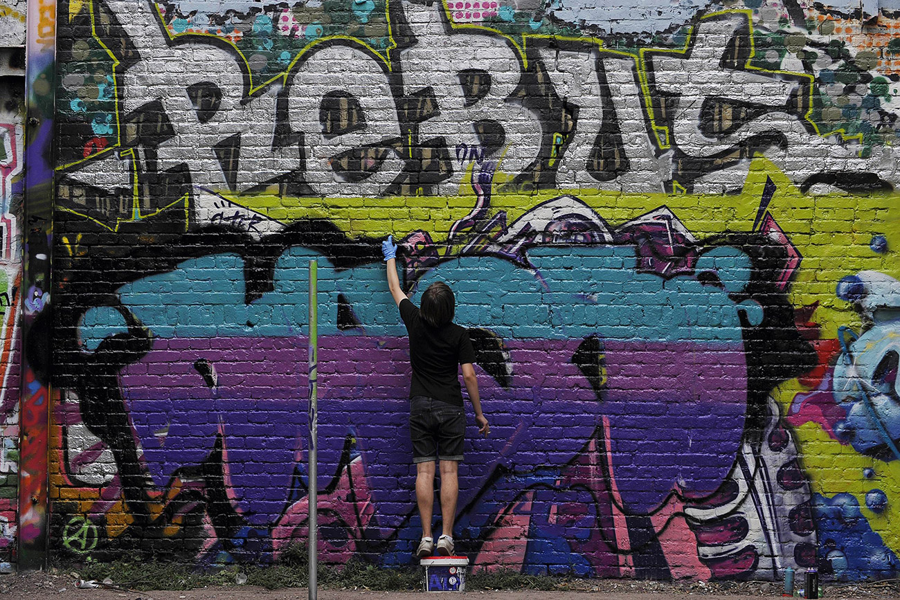 Russian teenager paints a graffiti on the wall  in Moscow. / Photo: AFP