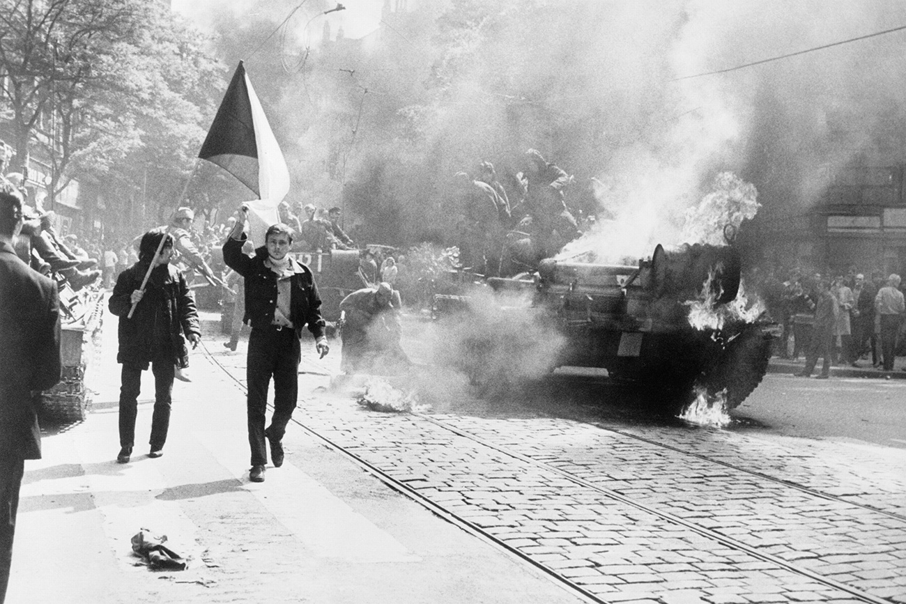 During the Soviet invasion of Czechoslovakia, Czechoslovaks carry their national flag past a burning tank in Prague 1968. Source: The Central Intelligence Agency