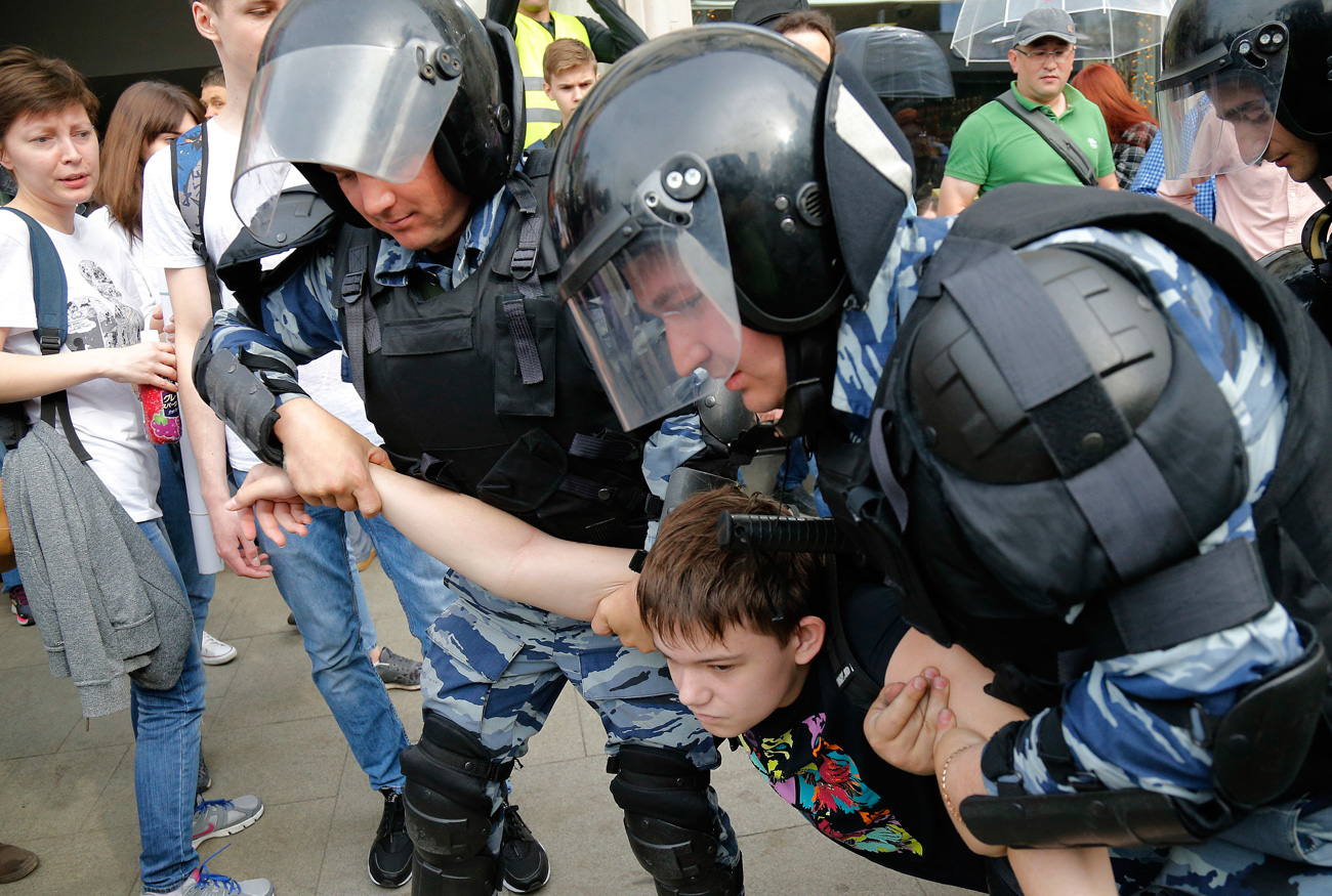 A young demonstrator is apprehended by riot police during a demonstration in downtown Moscow, June 12, 2017. / AP