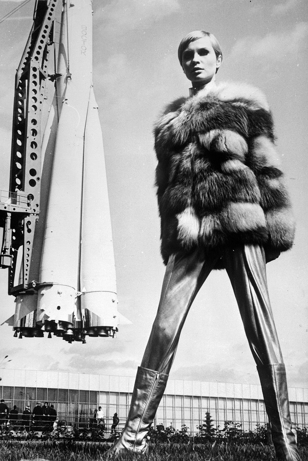 Space-age styling from Russian designers, as Moscovite model Galina Milovskaya wears a metallic ensemble with a red fox fur jacket, leggings and silver boots, the look is completed by the Vostock space rocket in the background. / Getty Images