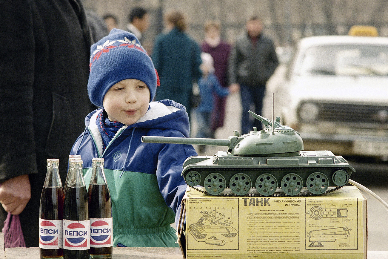 Un bambino osserva un carro armato in miniatura vicino ad alcune bottiglie di Pepsi. Mosca, 1992. Fonte: AP