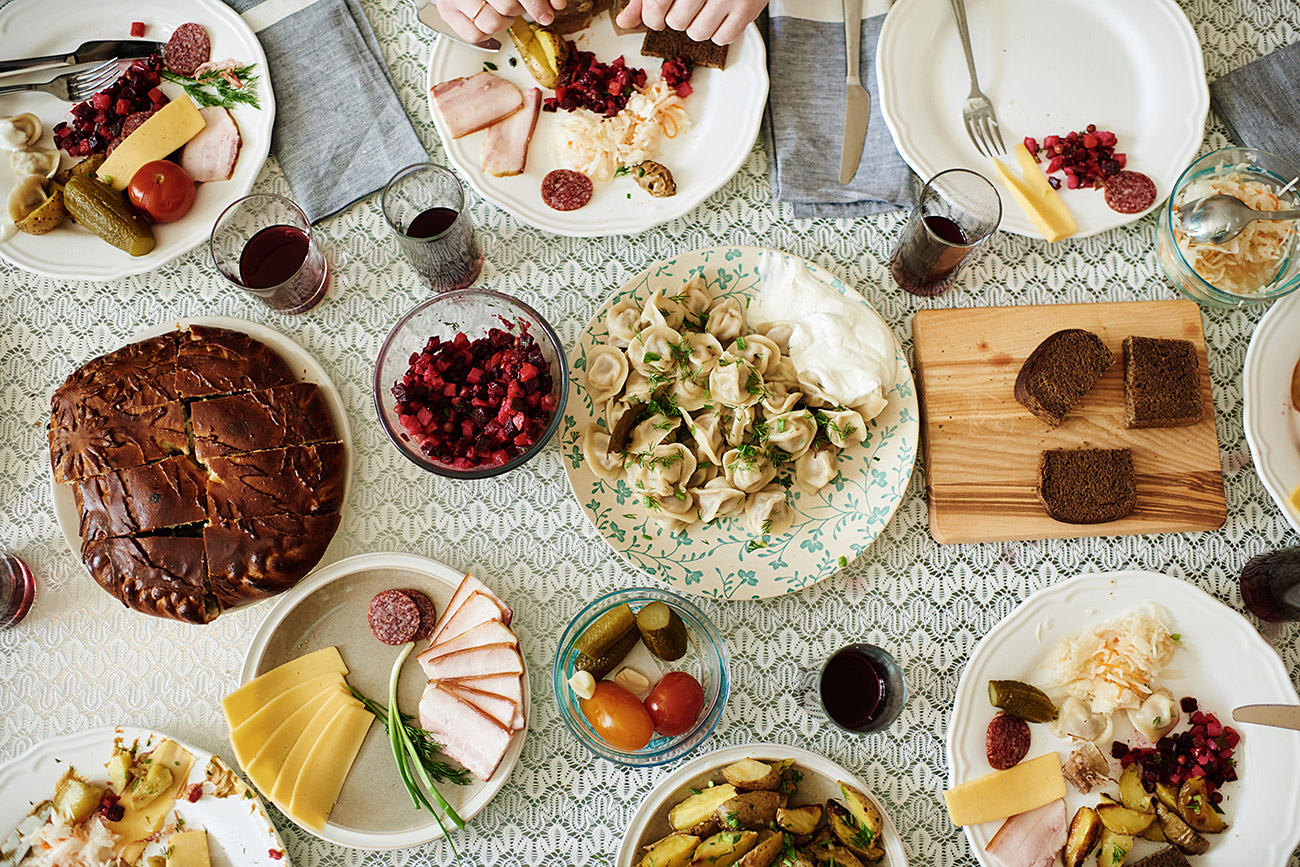 Traditional Russian food served on dining table: homemade pelmeni, vinegret salsd, cold cuts, pie and pickles / Getty Images