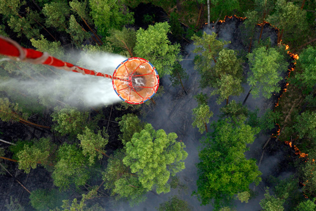 An Emergencies Ministry MI-8MTV-2 helicopter carries water before releasing it over the burning Taiga wood near the village of Boguchany, about 560 km (348 miles) northeast of Russia's Siberian city of Krasnoyarsk, June 2, 2011. Dry, hot weather, dry thunder storms and human factors influenced the distribution of the fires in Siberia, according to Emergencies Ministry members. Picture taken June 2, 2011. REUTERS/Ilya Naymushin