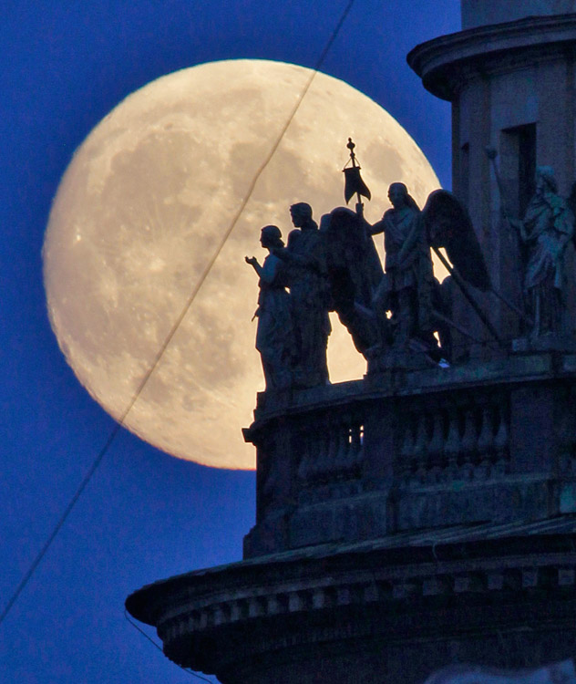 Statues of angels fixed at the St. Isaak's Cathedral are silhouetted on the full moon in St.Petersburg, Russia, early Wednesday, June 15, 2011. (AP Photo/Dmitry Lovetsky)