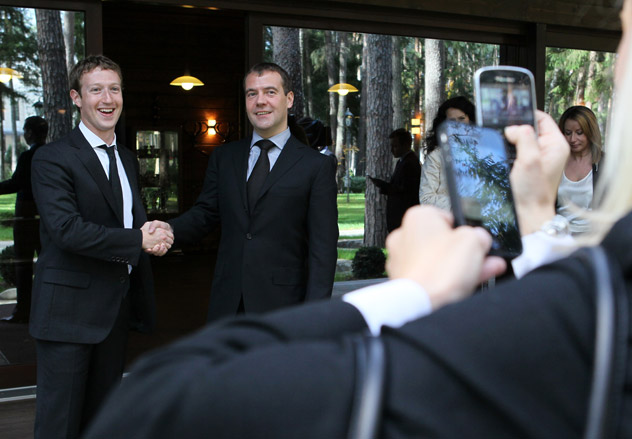 A blonde woman taking pictures with an iPhone of Prime Minister of Russia Dmitry Medvedev (R) and Facebook's founder, Mark Zuckerberg, during their meeting. Source: ITAR-TASS.