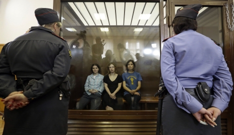 Feminist punk group Pussy Riot members, from left, Yekaterina Samutsevich, Maria Alekhina and Nadezhda Tolokonnikova sit in a glass cage at a court room in Moscow, Russia. Source: AP