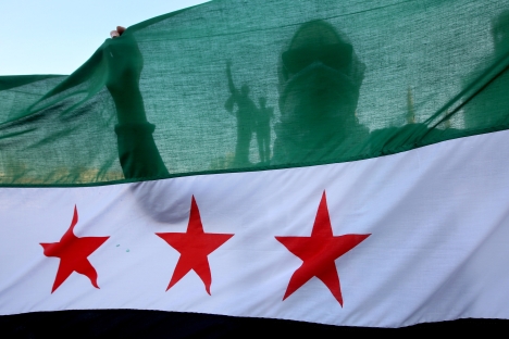 A Syrian activist is silhouetted through the Syrian revolution flag during a protest against the participation of Hezbollah members in the fighting in the Syrian town of Qusair, at the Martyrs square in Beirut, Lebanon, Tuesday May 21, 2013. Source: AP