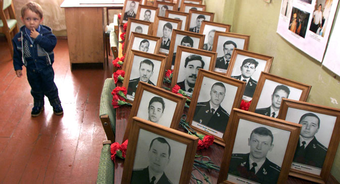 A Russian boy stands by portraits of Kursk submarine victims in their barracks during a memorial ceremony in the Russian Arctic port of Vidyayevo, August 12, 2001. Source: Reuters