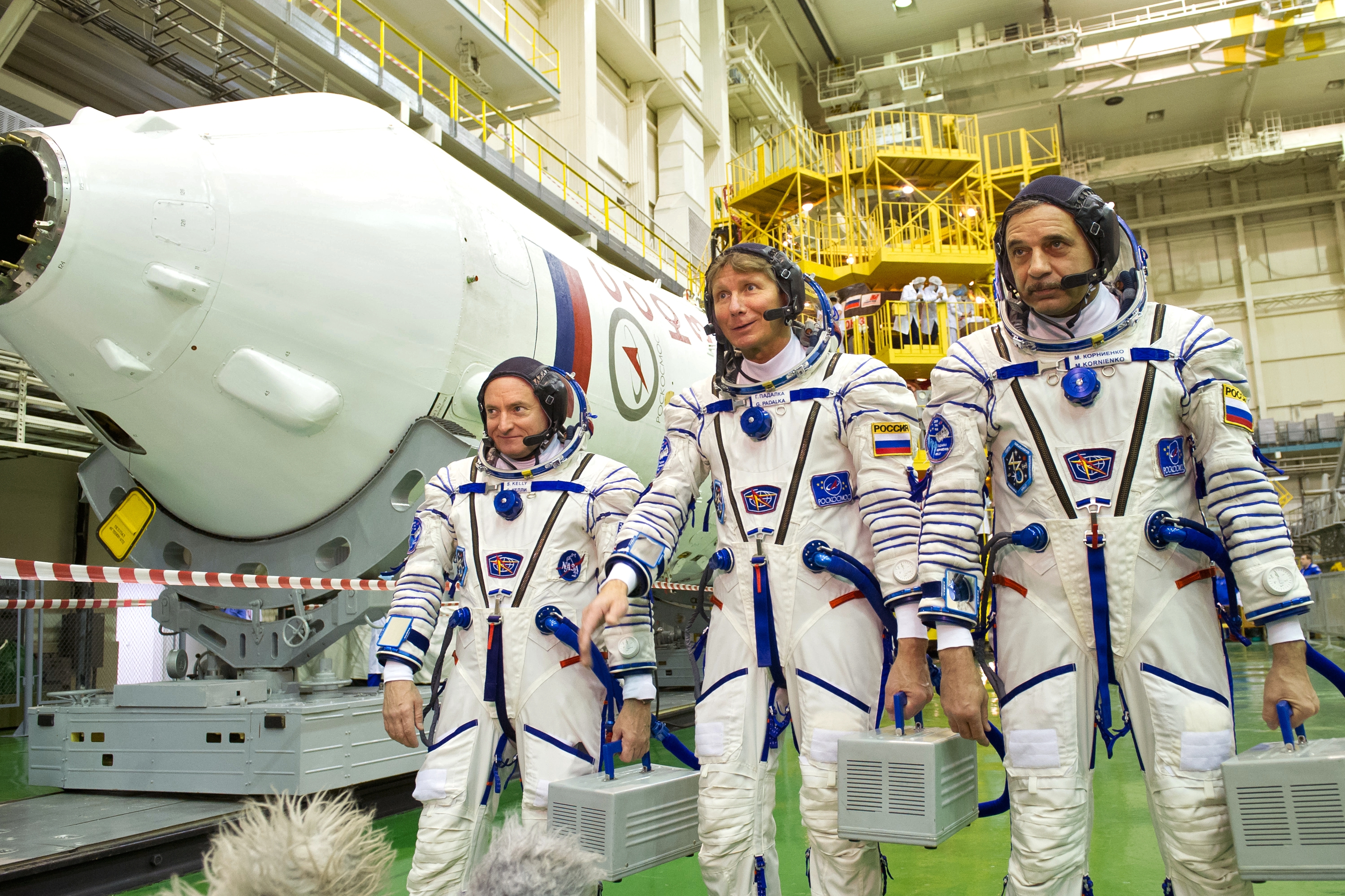 Членови на екипажот ТМА-16М од експедицијата 43/44 на Меѓународната вселенска станица, ги пробаат скафандерите на космодромот Бајконур, од лево кон десно: Скот Кели (САД), Генадиј Падалка (Русија) и Михаил Корноенко (Русија). Извор: РИА Новости 